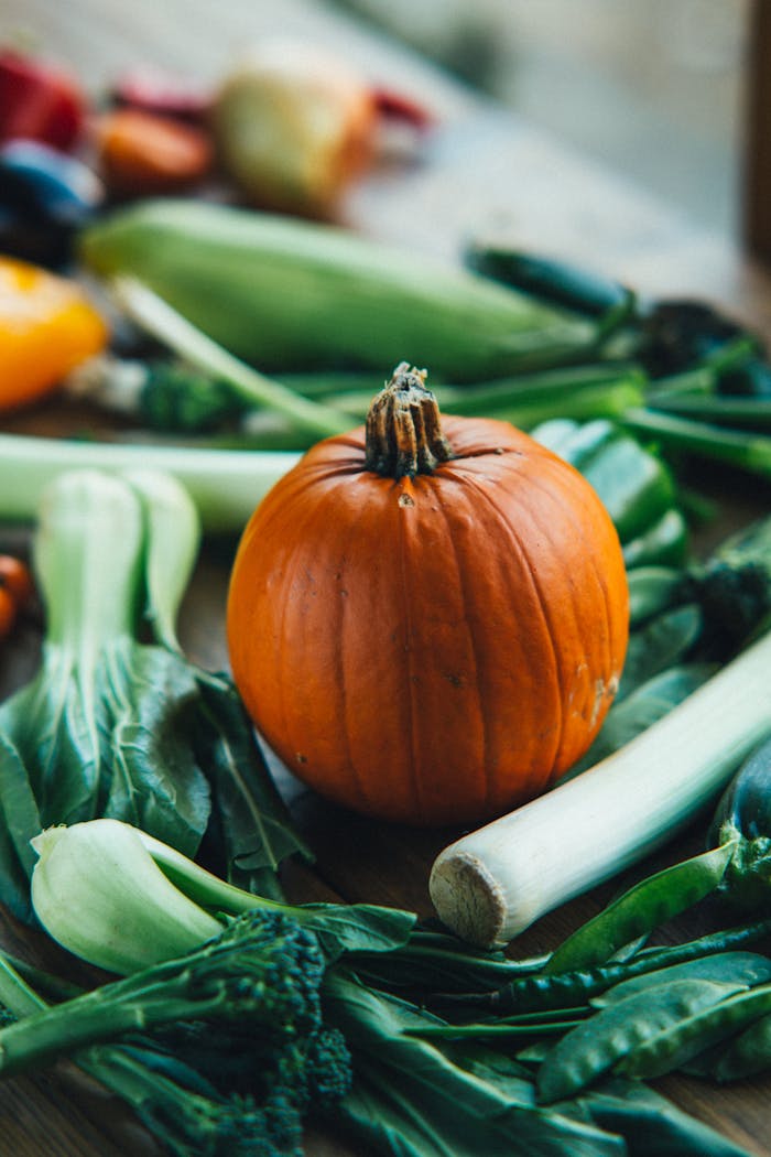 A vibrant display of fresh vegetables including pumpkin, leek, and greens on a rustic wooden table.